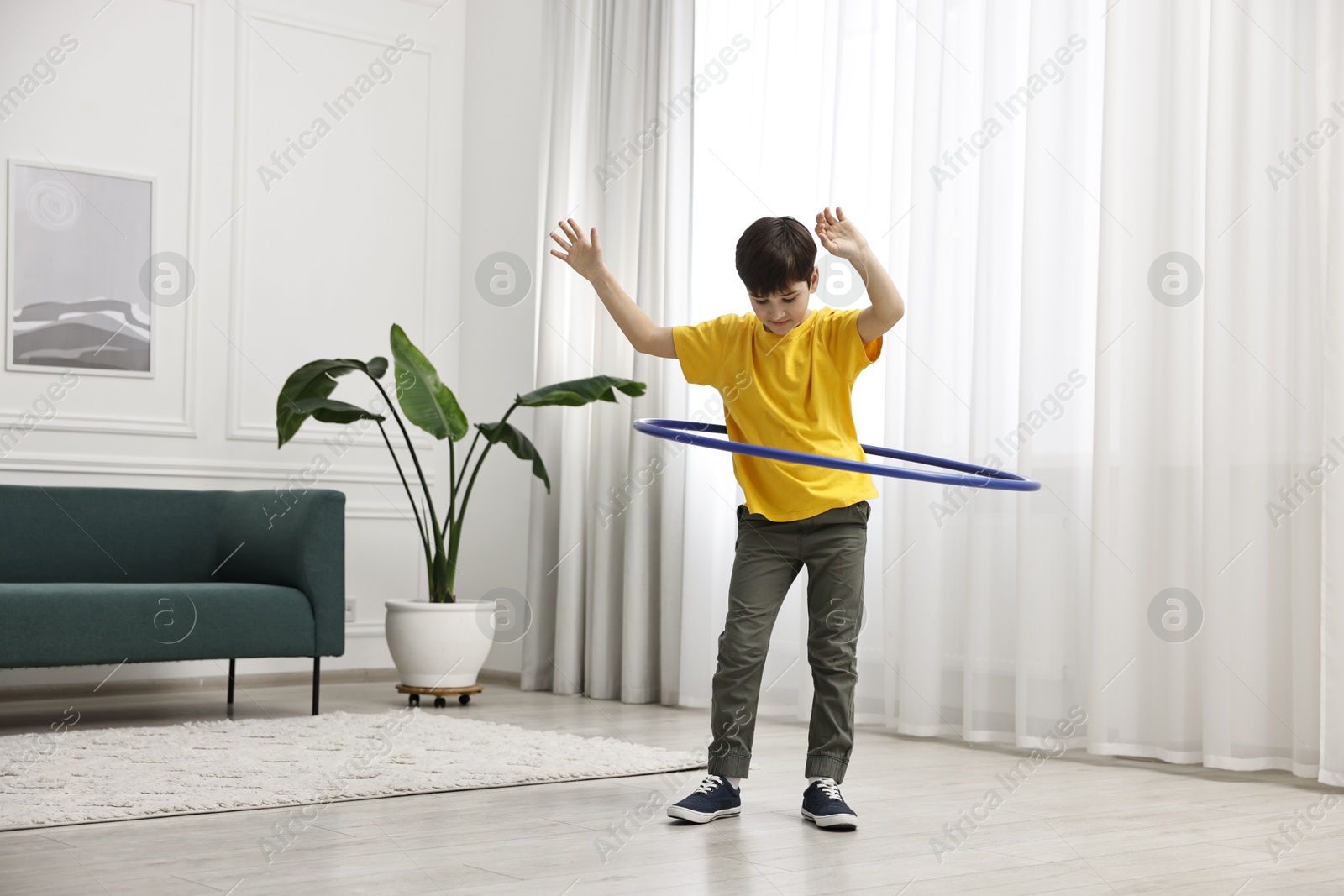 Photo of Boy exercising with hula hoop at home