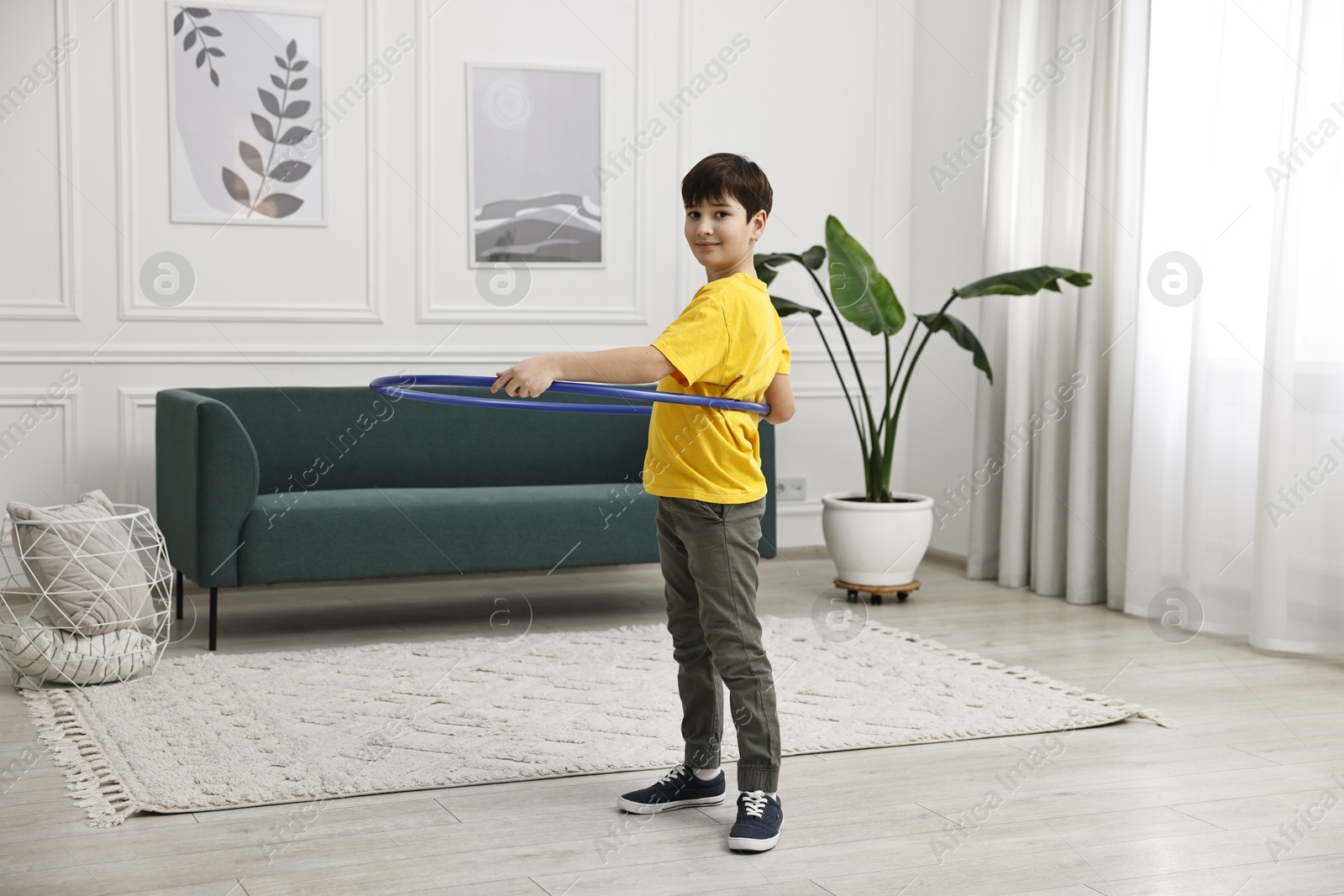 Photo of Boy exercising with hula hoop at home