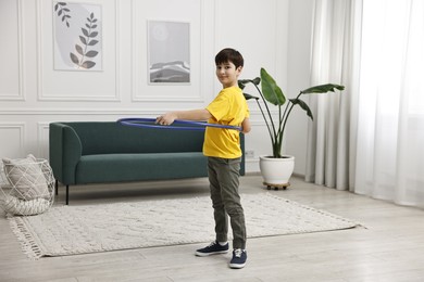 Photo of Boy exercising with hula hoop at home