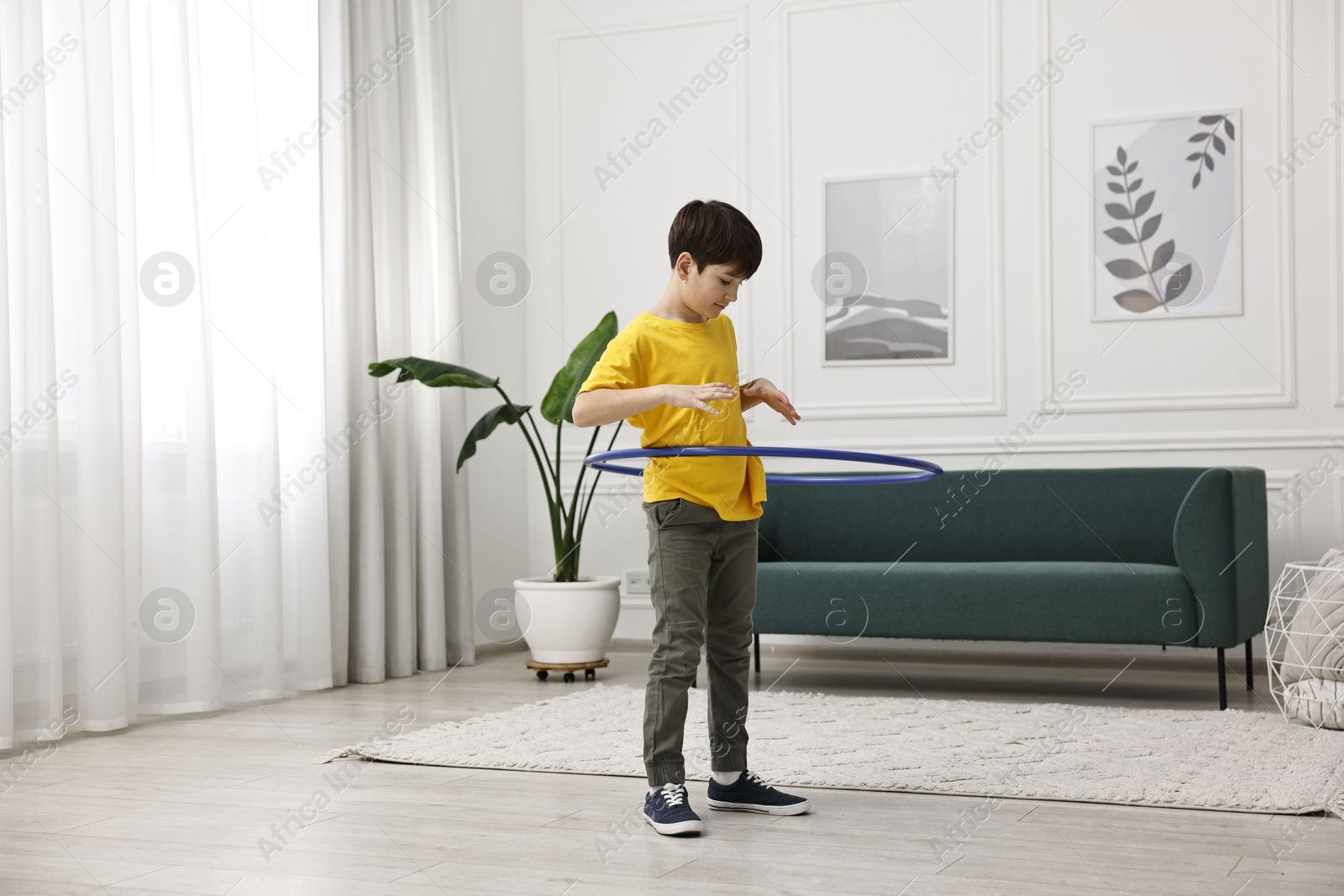 Photo of Boy exercising with hula hoop at home