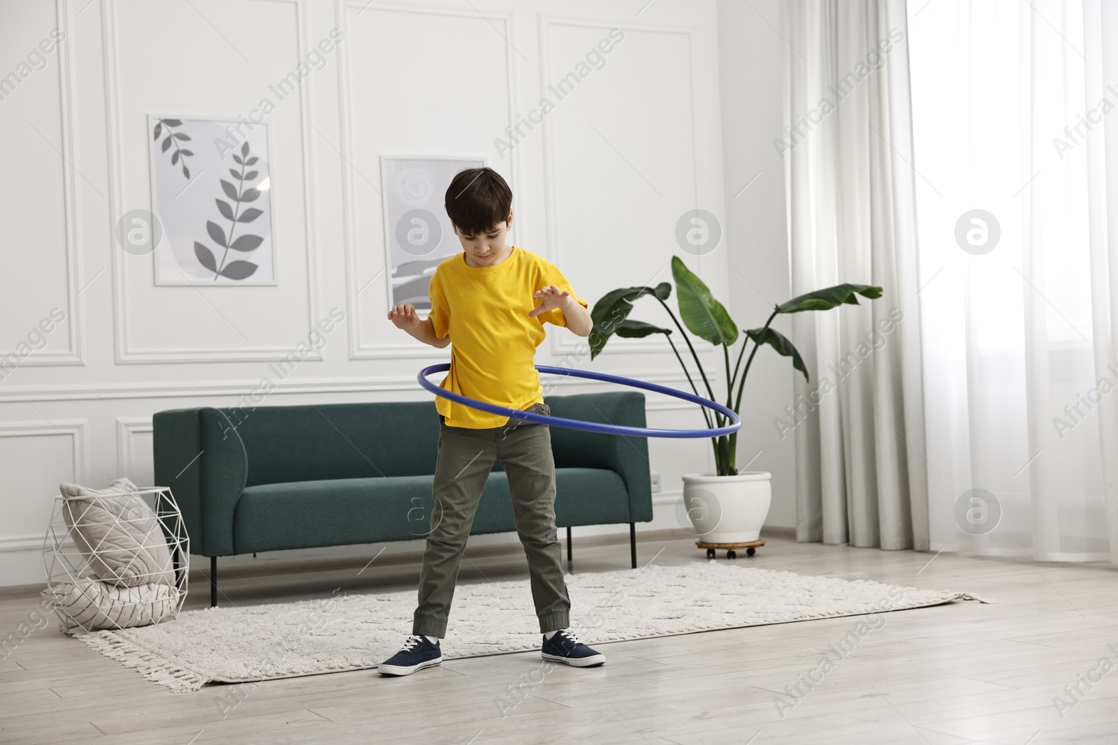 Photo of Boy exercising with hula hoop at home