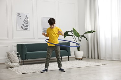 Photo of Boy exercising with hula hoop at home