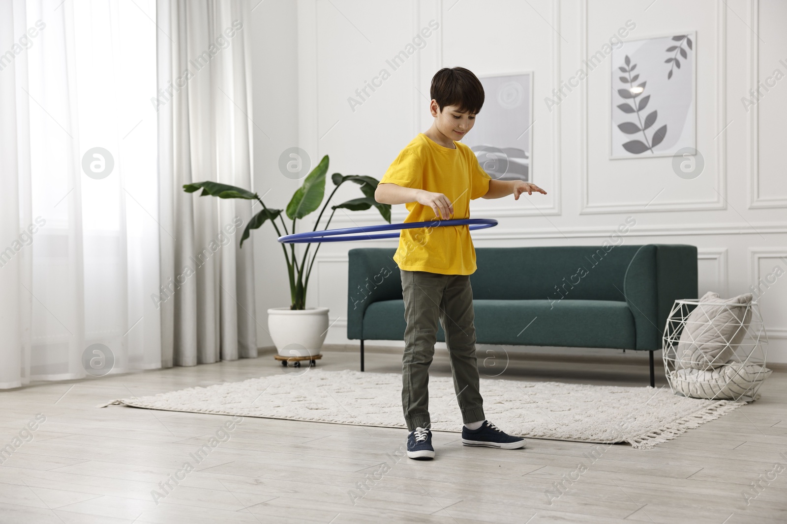 Photo of Boy exercising with hula hoop at home