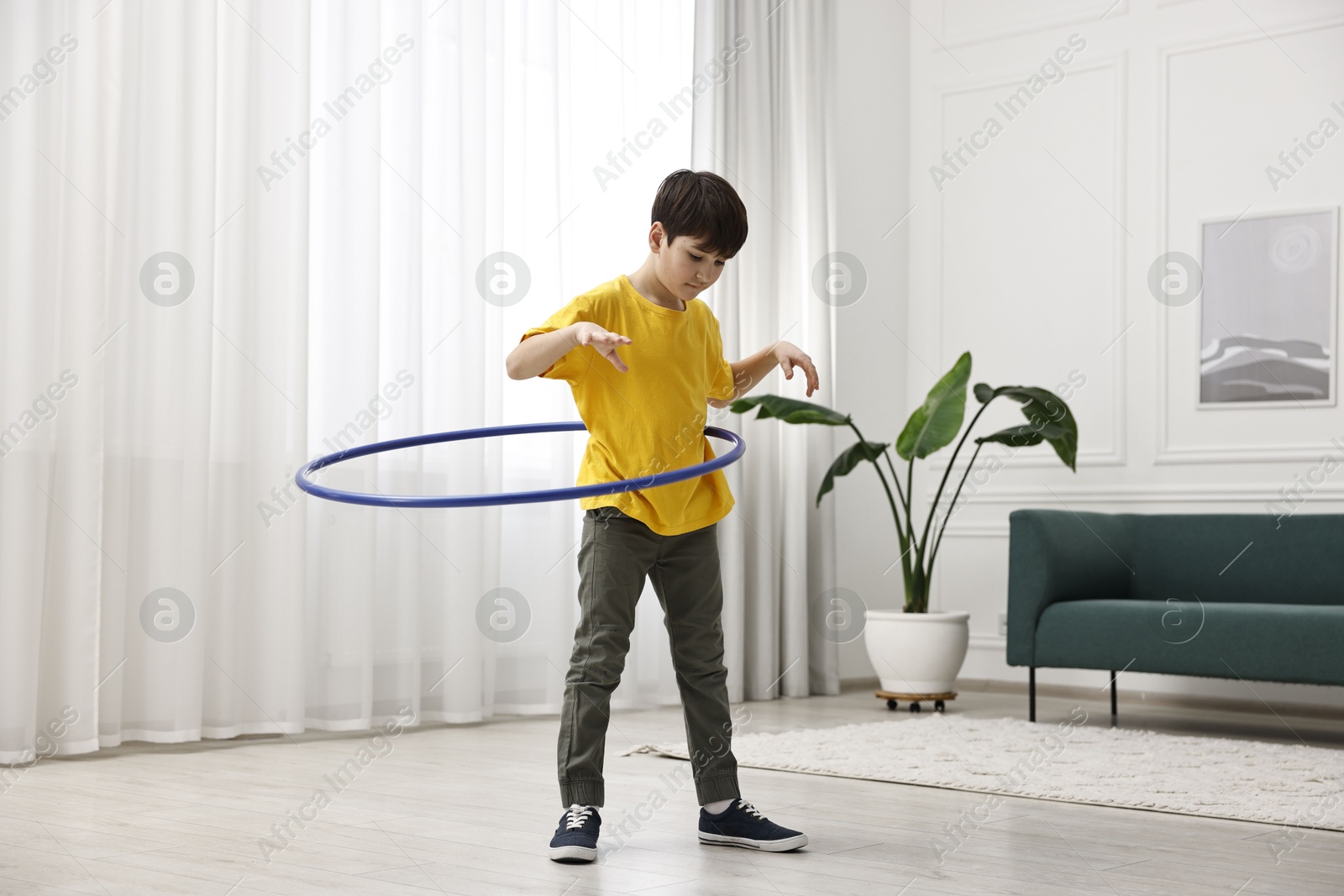 Photo of Boy exercising with hula hoop at home