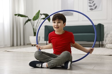 Photo of Smiling boy with hula hoop on floor at home