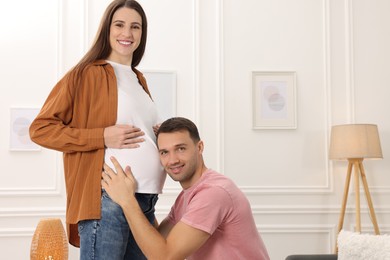 Photo of Man listening to baby in his pregnant wife's belly at home. Space for text