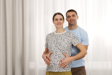 Photo of Pregnant woman and her husband at home. Space for text