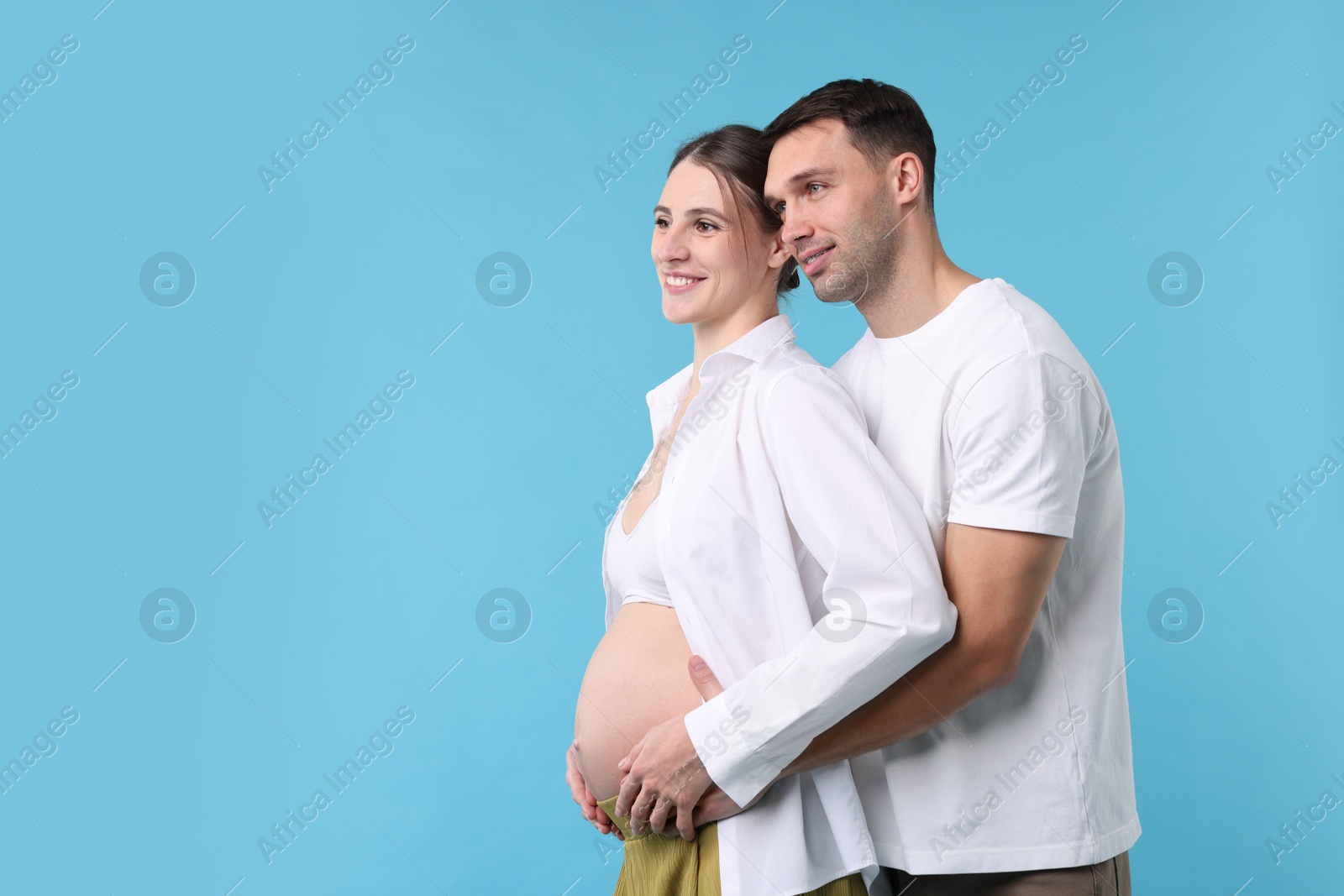 Photo of Pregnant woman and her husband on blue background. Space for text