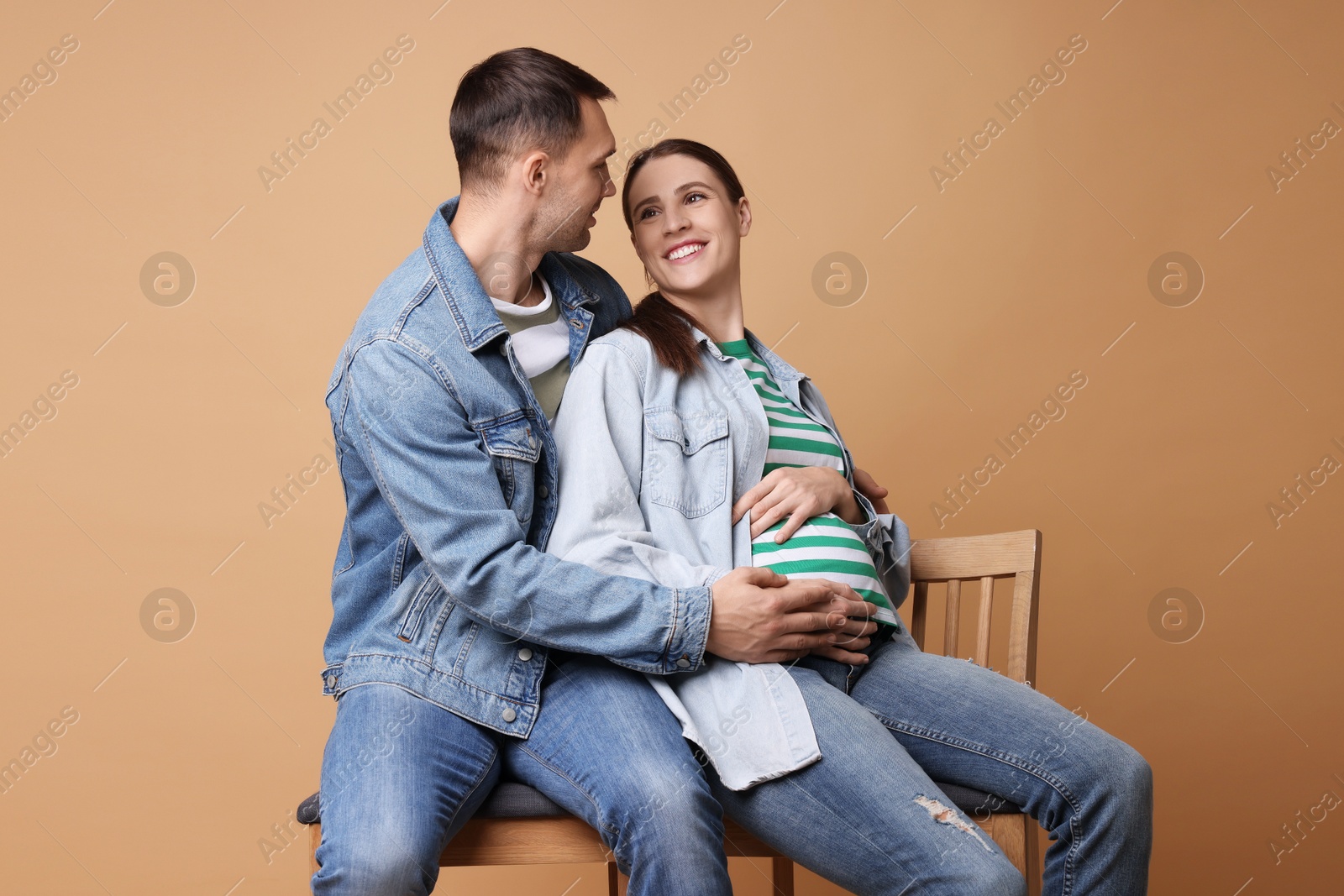 Photo of Pregnant woman and her husband on beige background