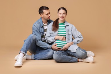 Photo of Pregnant woman and her husband on beige background