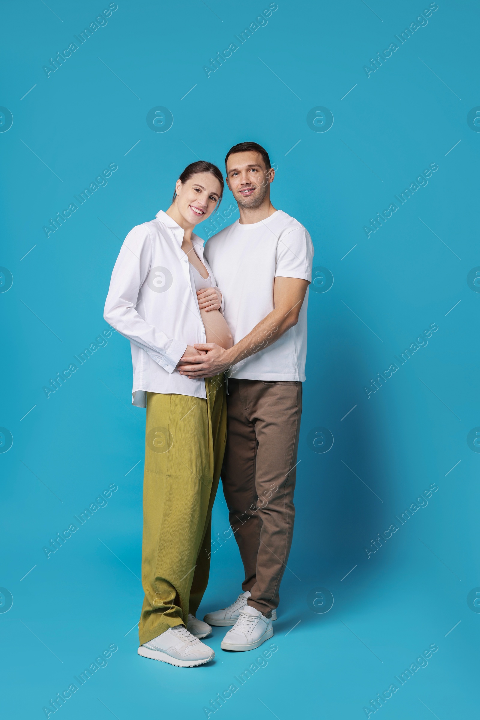 Photo of Pregnant woman and her husband on blue background