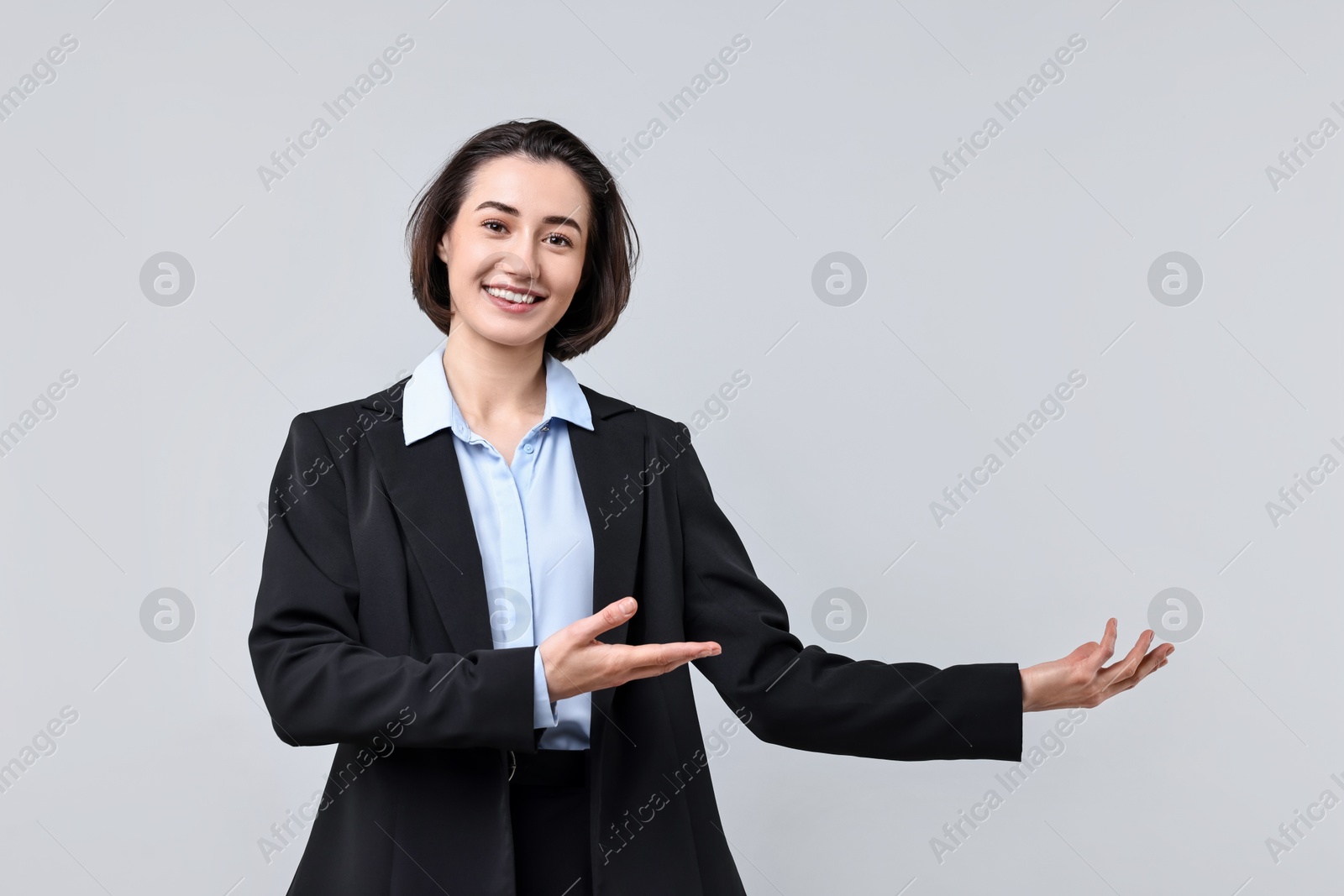 Photo of Happy businesswoman welcoming clients or partners on light grey background