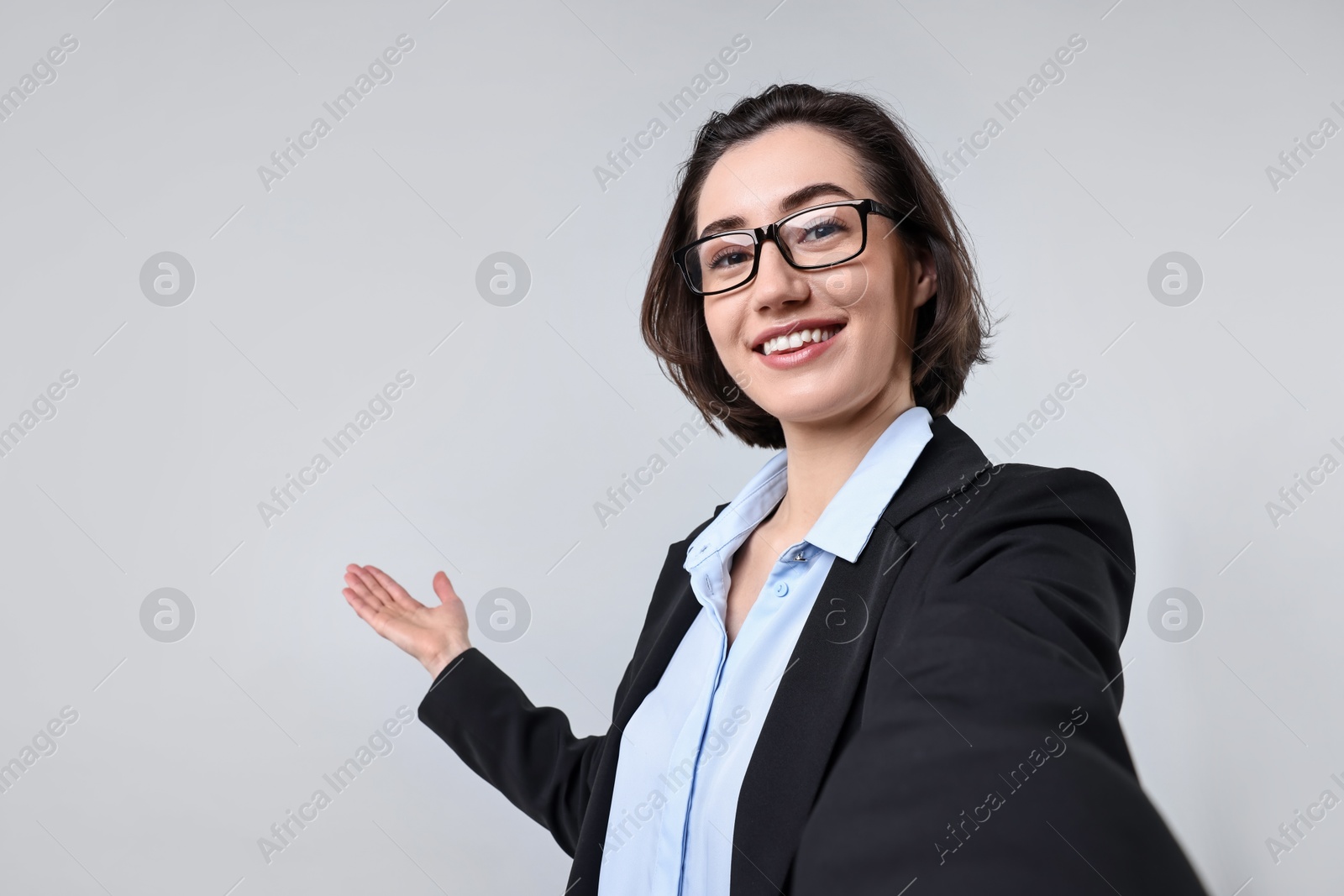 Photo of Happy businesswoman welcoming clients or partners via video call on light grey background