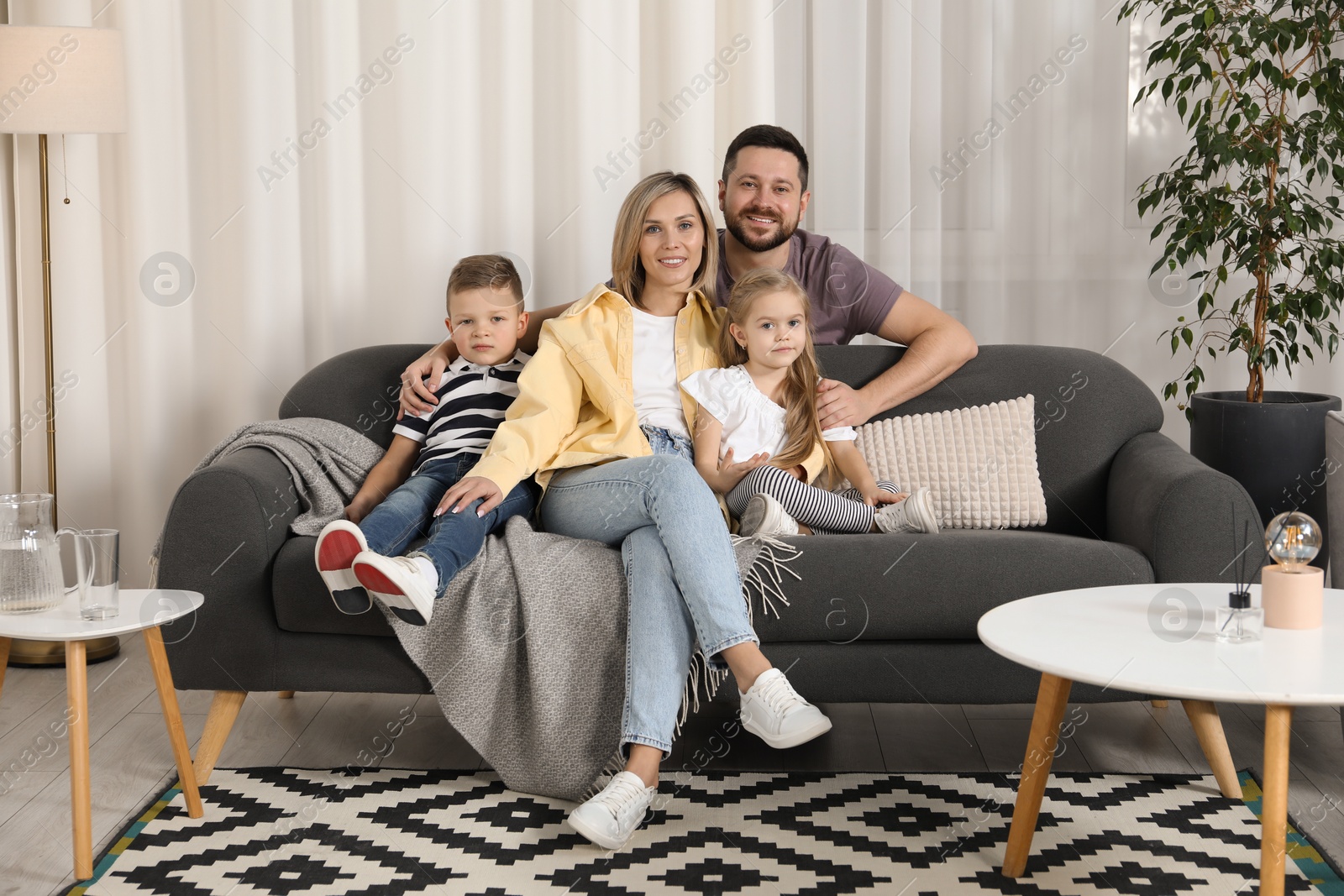 Photo of Happy parents and their children on sofa at home