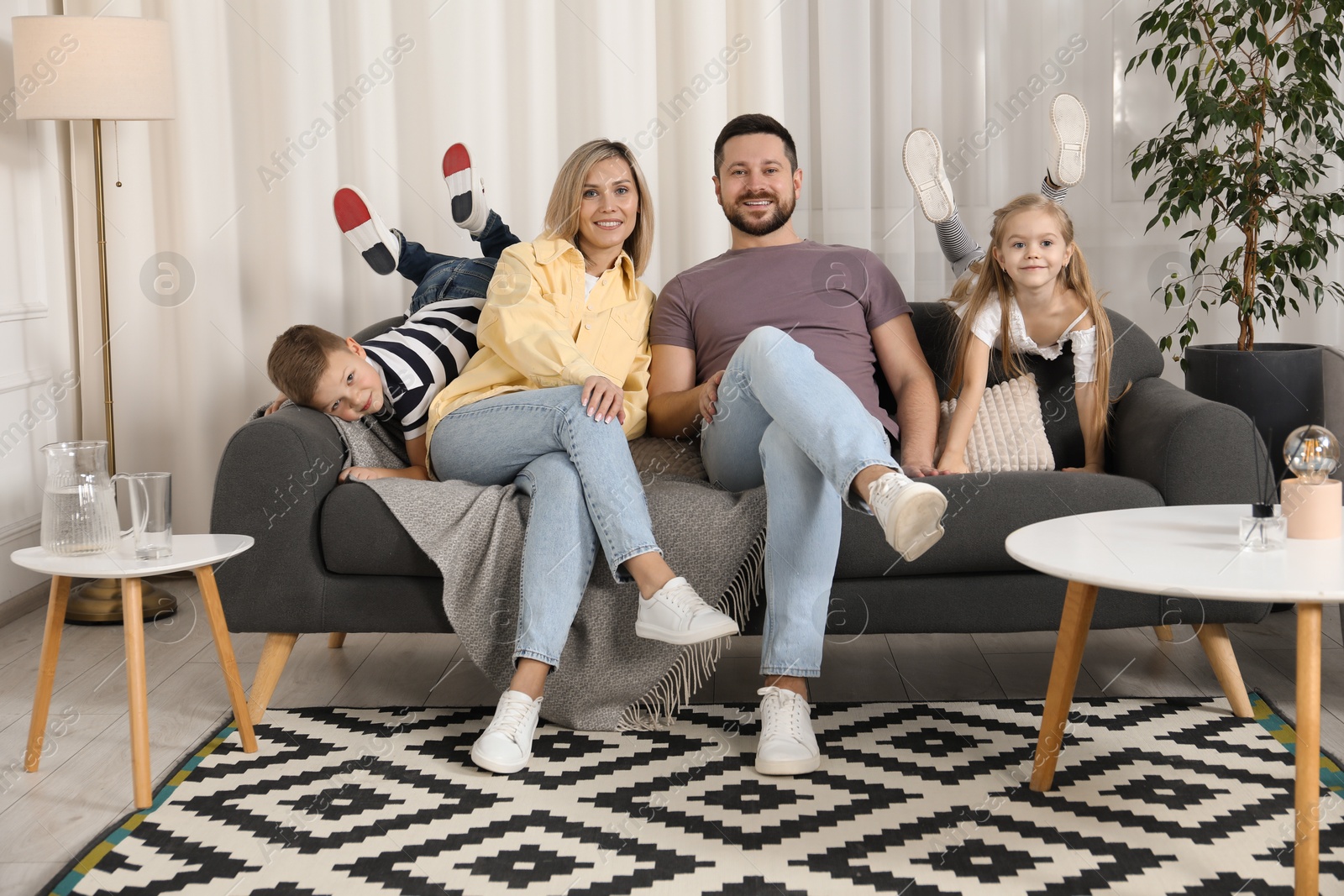 Photo of Happy parents and their children on sofa at home