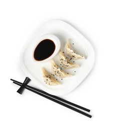 Photo of Tasty gyoza (dumplings), soy sauce and chopsticks isolated on white, top view