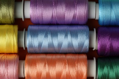 Photo of Different spools of sewing threads on table, top view