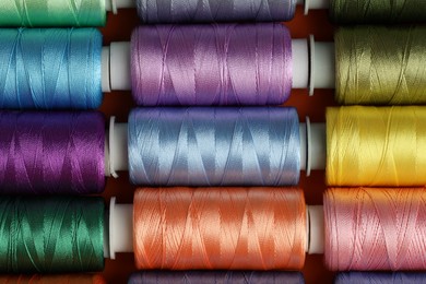 Photo of Different spools of sewing threads on table, top view