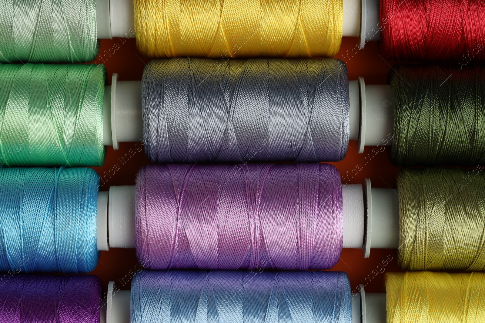 Photo of Different spools of sewing threads on table, top view