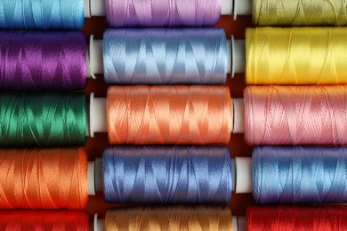 Photo of Different spools of sewing threads on table, top view