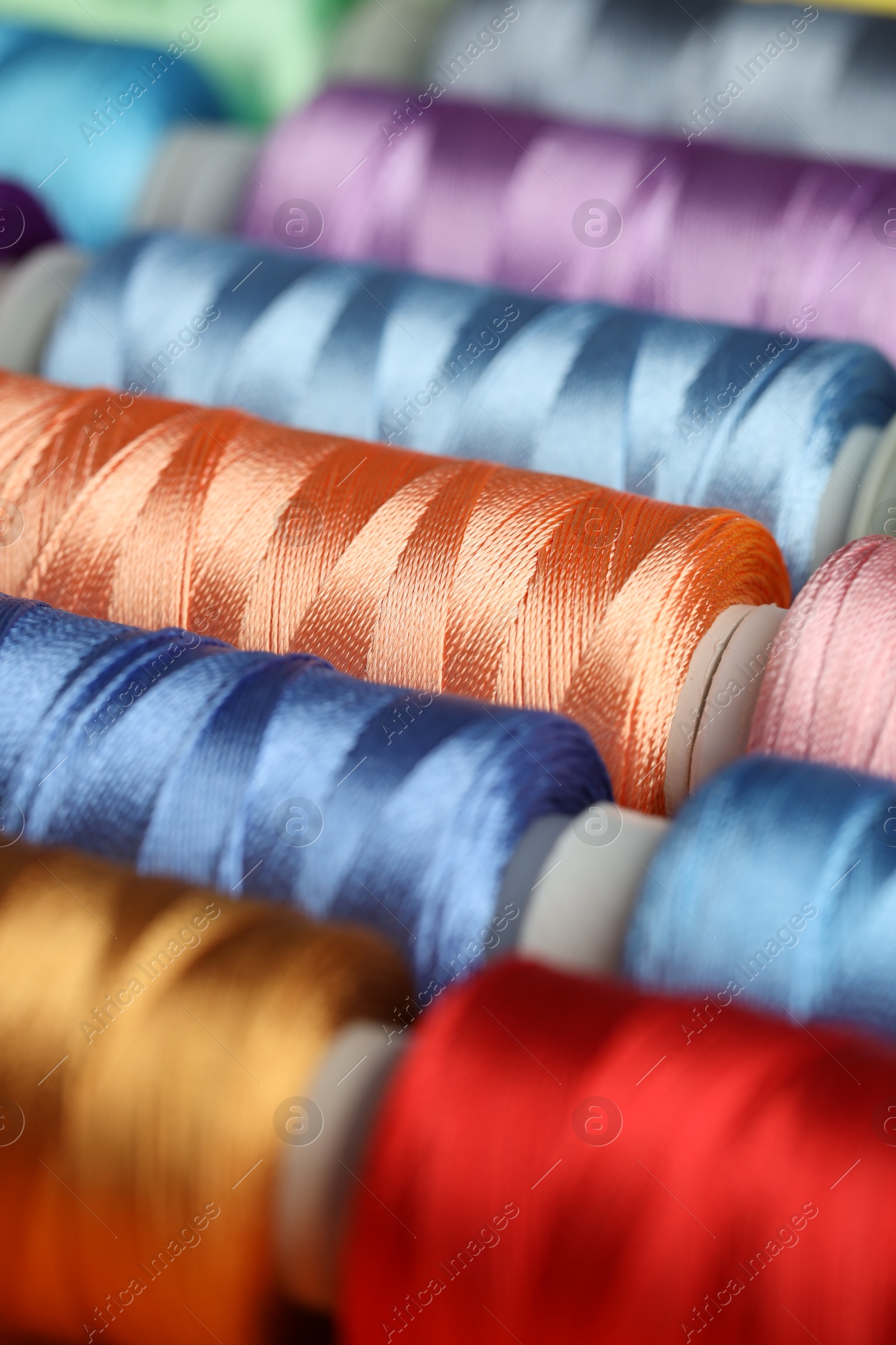 Photo of Different spools of sewing threads as background, closeup