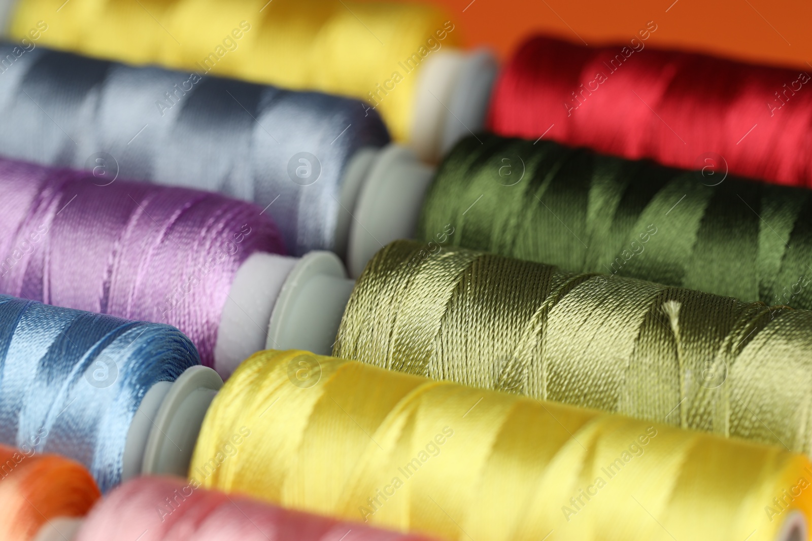 Photo of Different spools of sewing threads as background, closeup