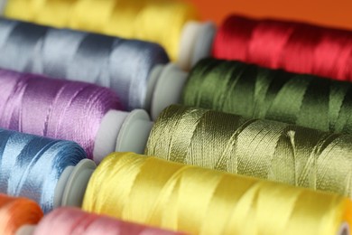 Photo of Different spools of sewing threads as background, closeup