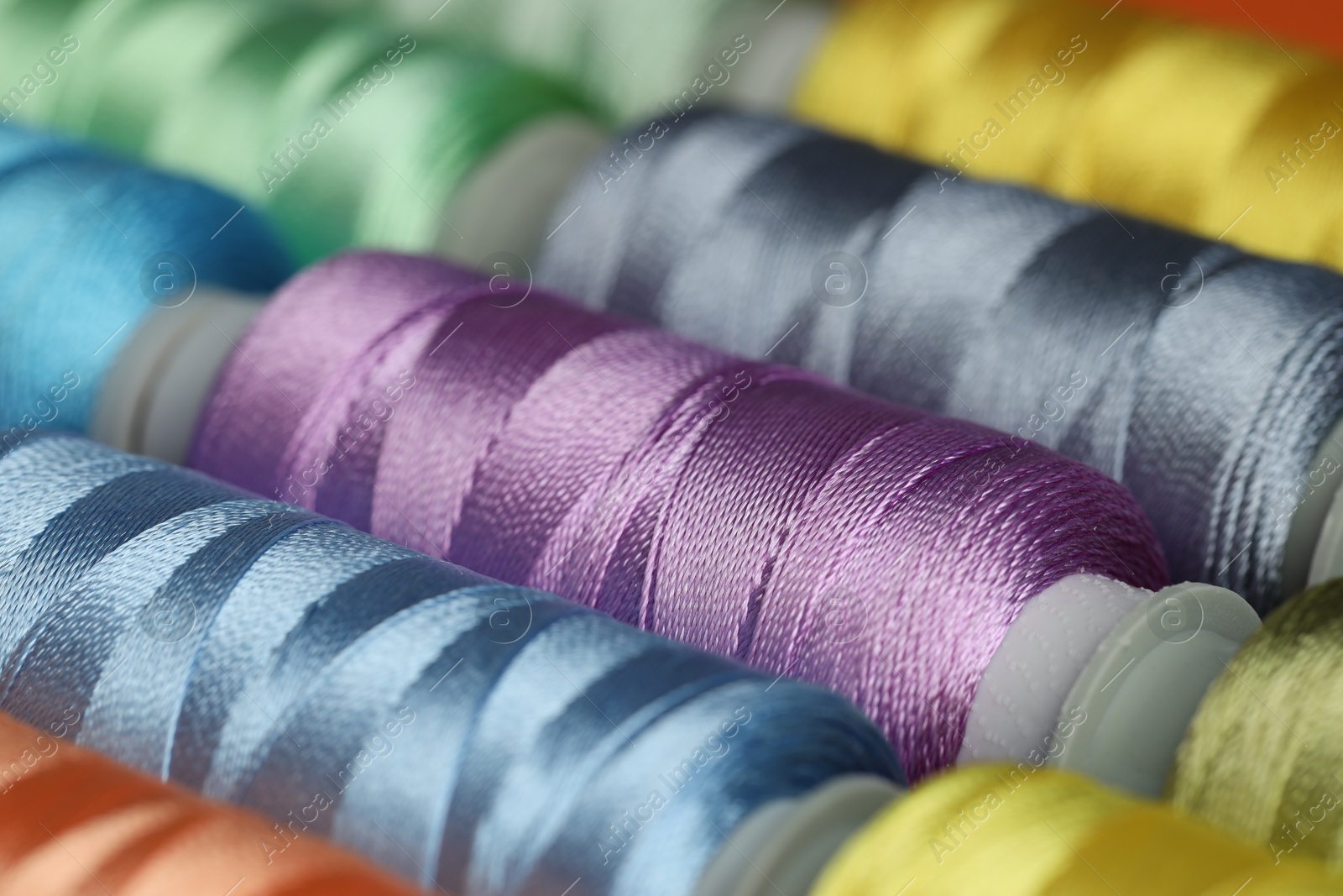 Photo of Different spools of sewing threads as background, closeup