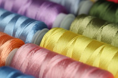 Photo of Different spools of sewing threads as background, closeup