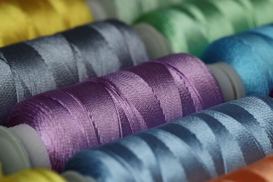 Photo of Different spools of sewing threads as background, closeup