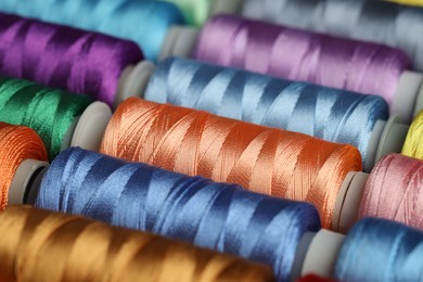 Photo of Different spools of sewing threads as background, closeup