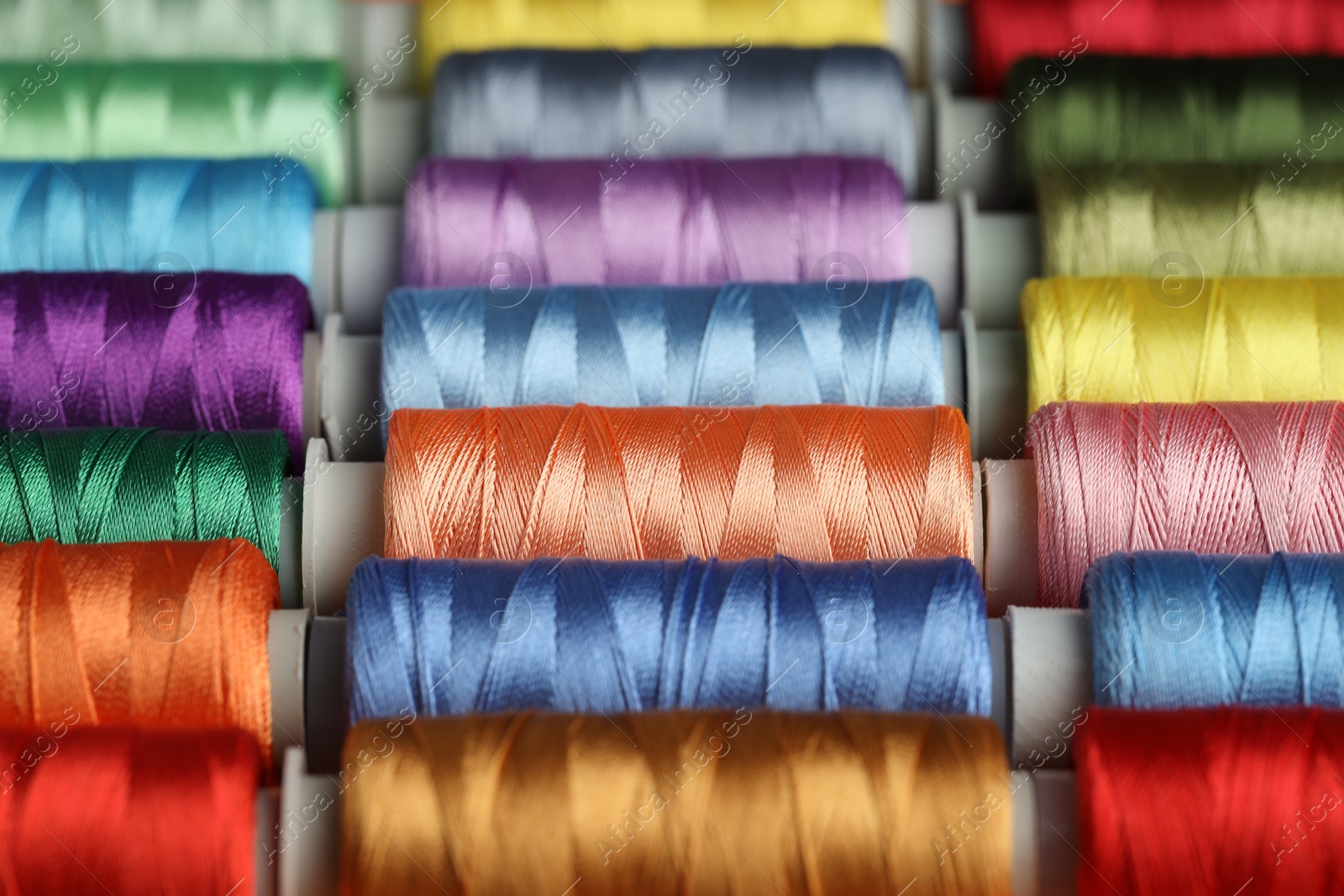 Photo of Different spools of sewing threads as background, closeup