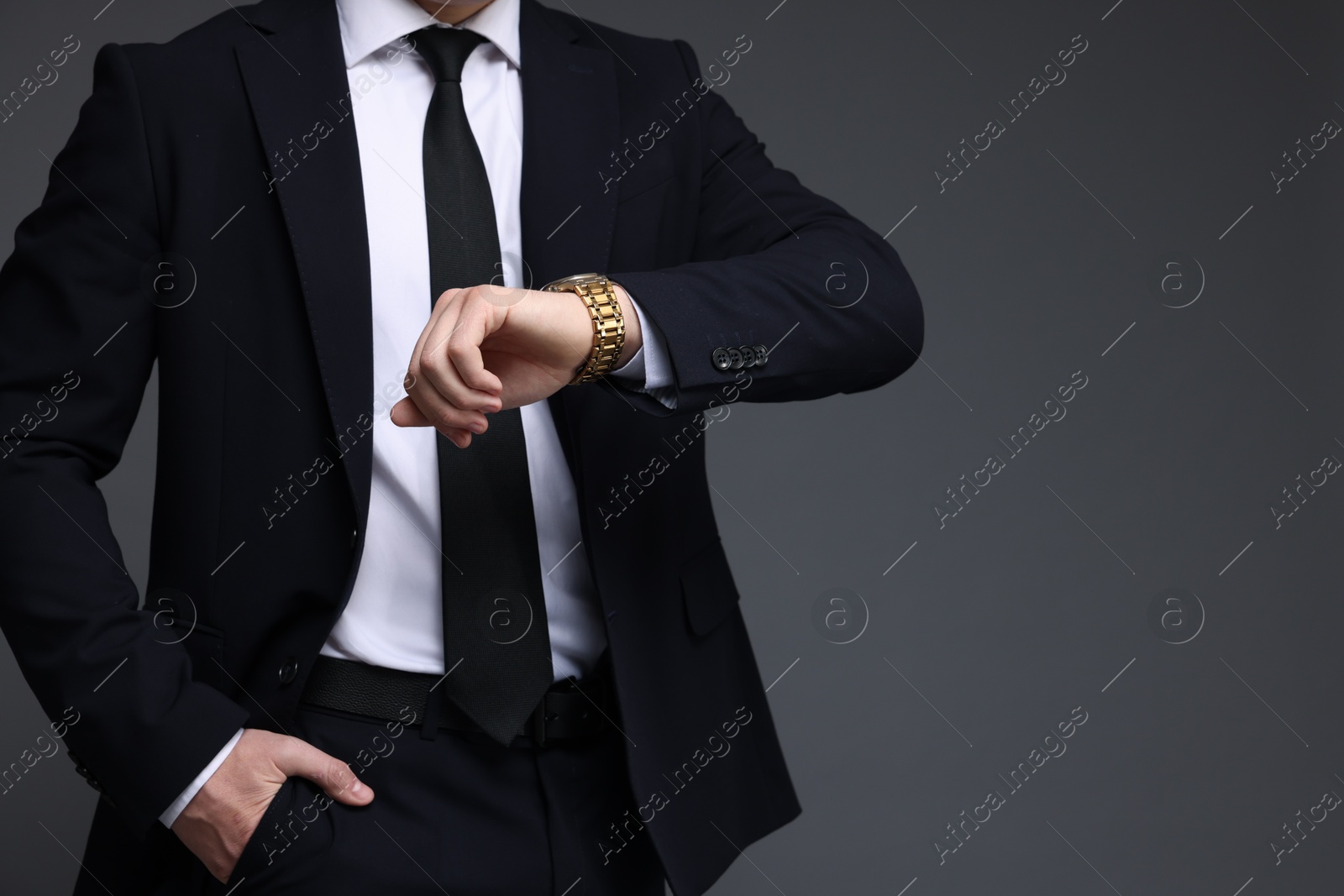 Photo of Man in classic suit checking time on grey background, closeup. Space for text