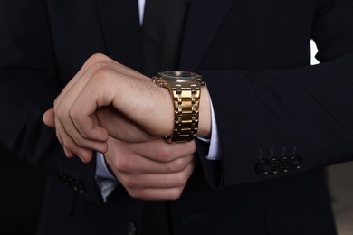 Photo of Man in classic suit with stylish watch on black background, closeup