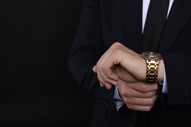 Photo of Man in classic suit with stylish watch on black background, closeup. Space for text