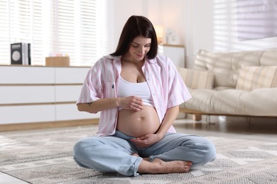 Photo of Beautiful pregnant woman with cute belly on floor at home