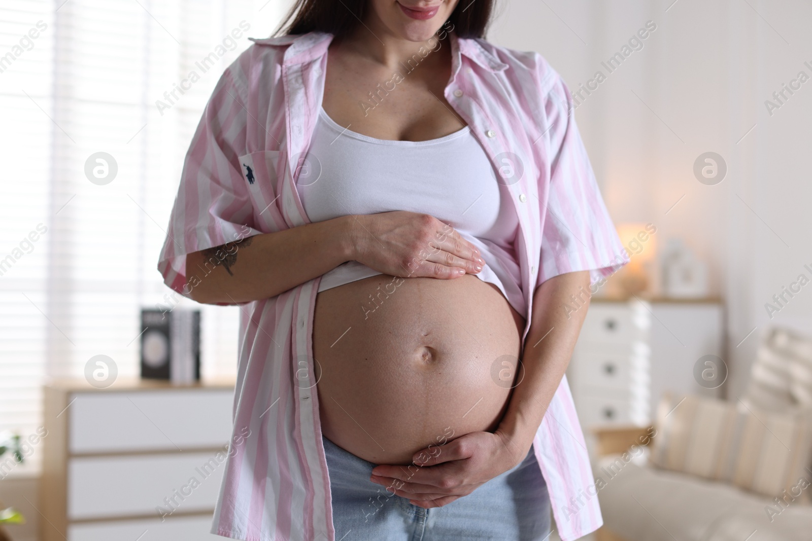 Photo of Beautiful pregnant woman with cute belly at home, closeup