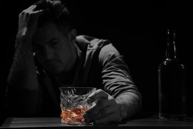 Image of Alcohol addiction. Drunk man with alcohol at table in darkness