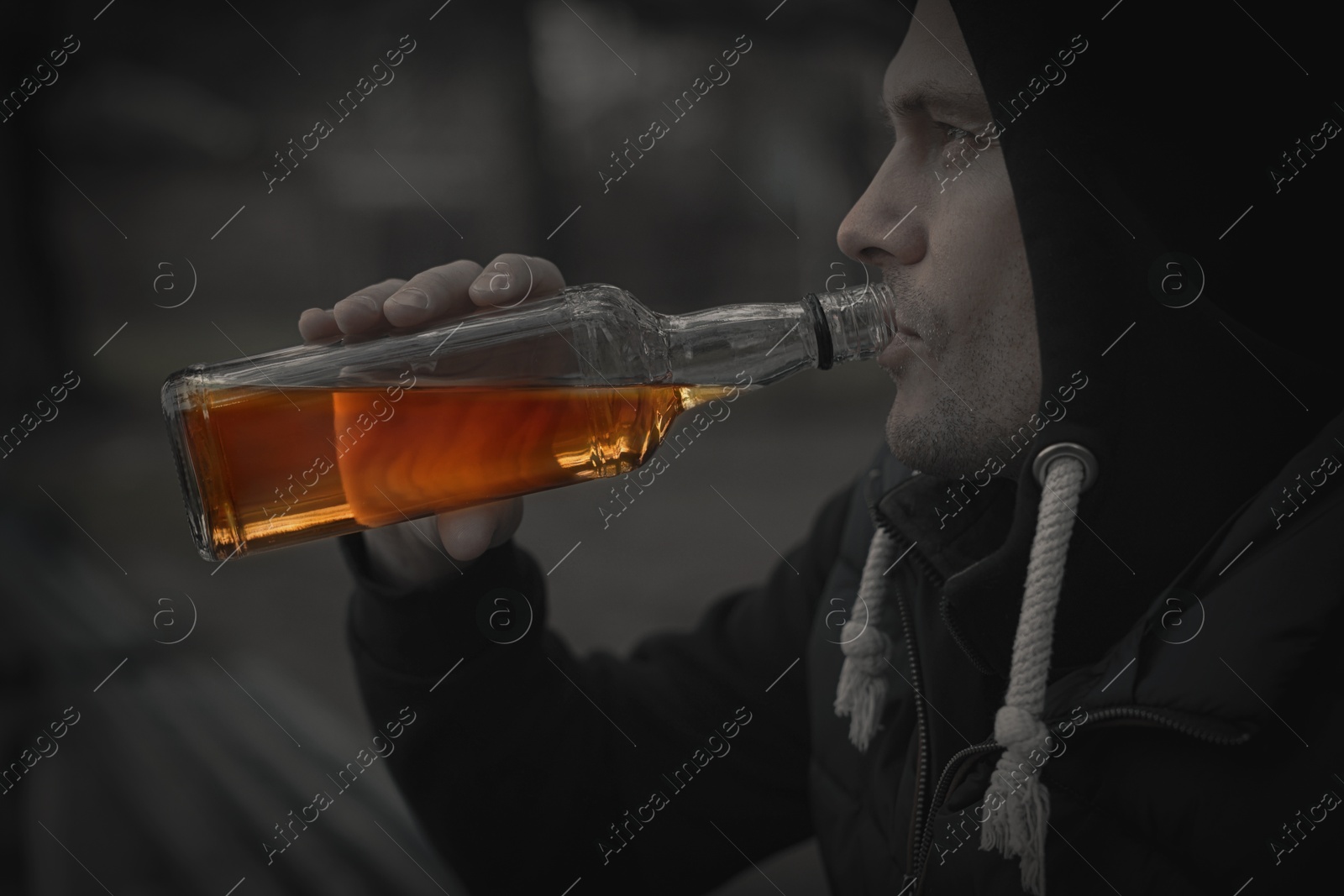 Image of Alcohol addiction. Man drinking alcohol from bottle outdoors, closeup