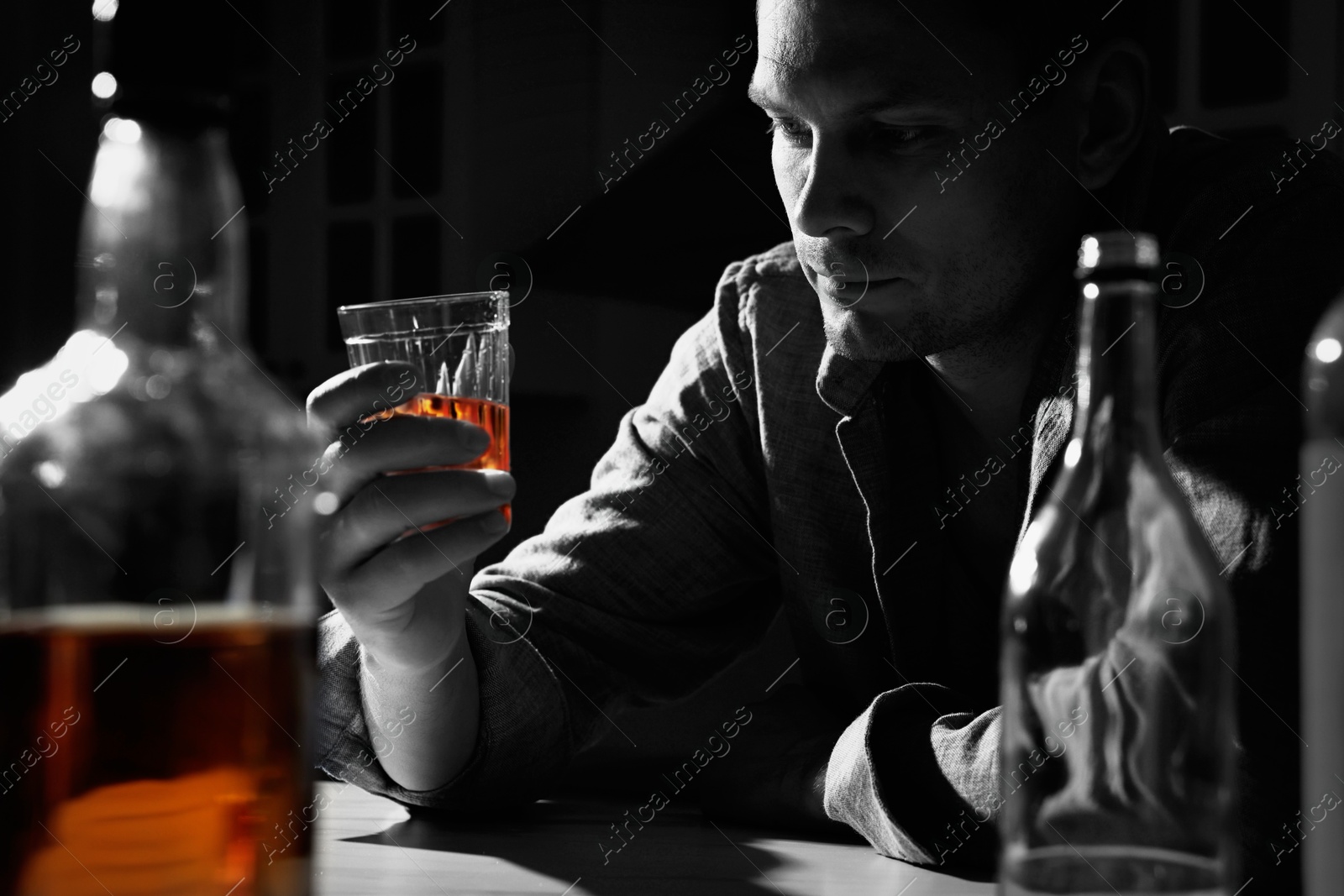 Image of Alcohol addiction. Depressed man with alcohol at table