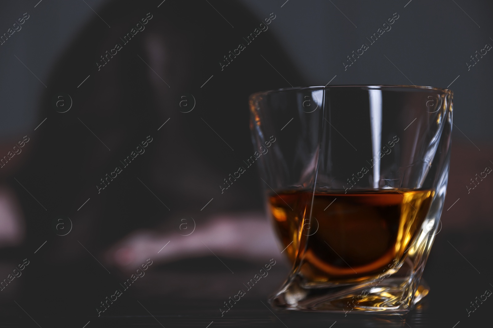 Image of Alcohol addiction. Drunk woman, focus on glass of whiskey