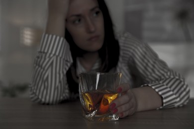 Image of Alcohol addiction. Woman with glass of whiskey at table, selective focus