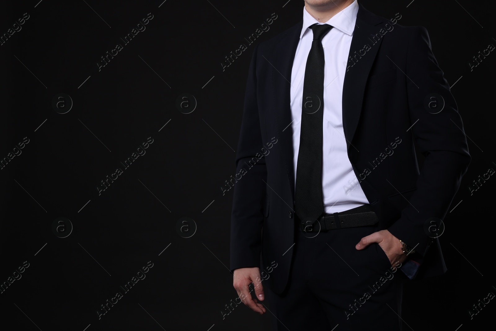 Photo of Man in classic suit on black background, closeup. Space for text