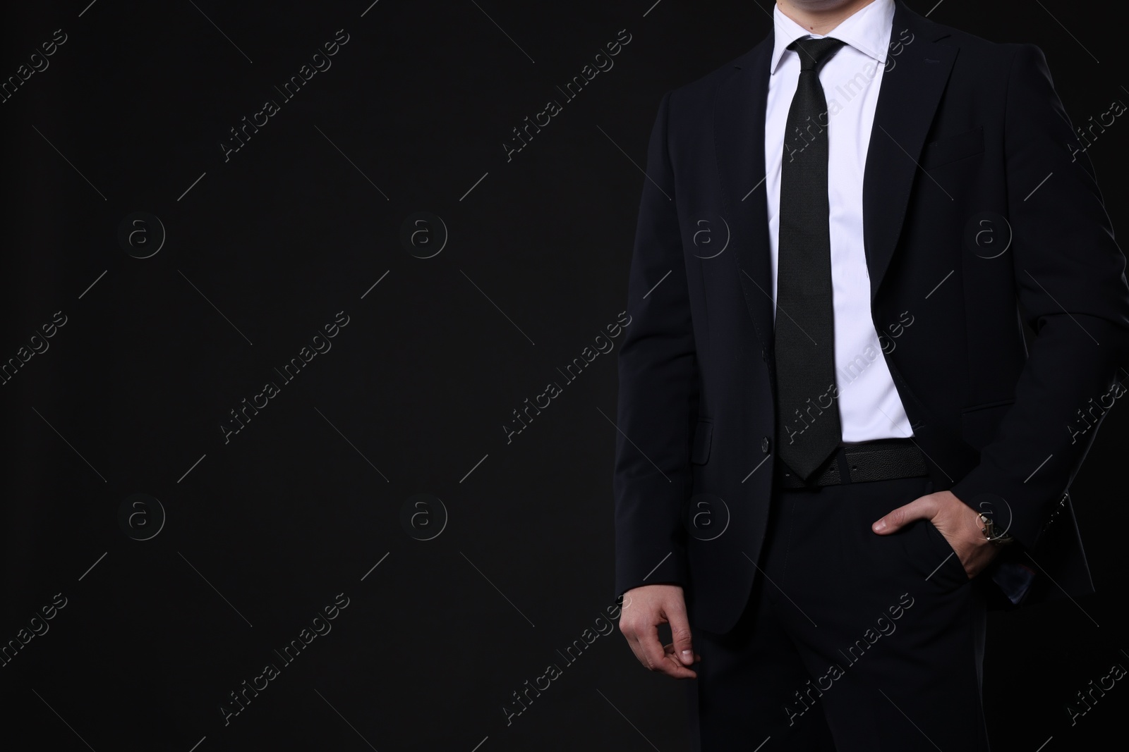 Photo of Man in classic suit on black background, closeup. Space for text