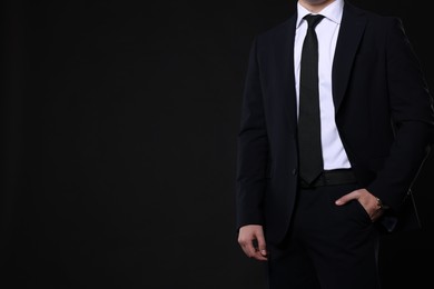 Photo of Man in classic suit on black background, closeup. Space for text