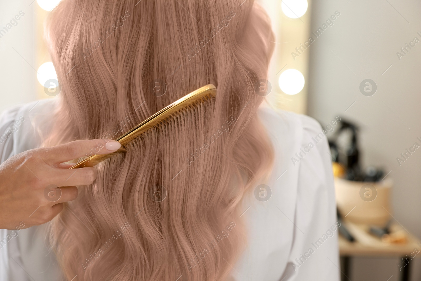 Image of Professional hairdresser combing woman's hair after dyeing in mocha mousse shade, closeup. Trendy color of 2025 year