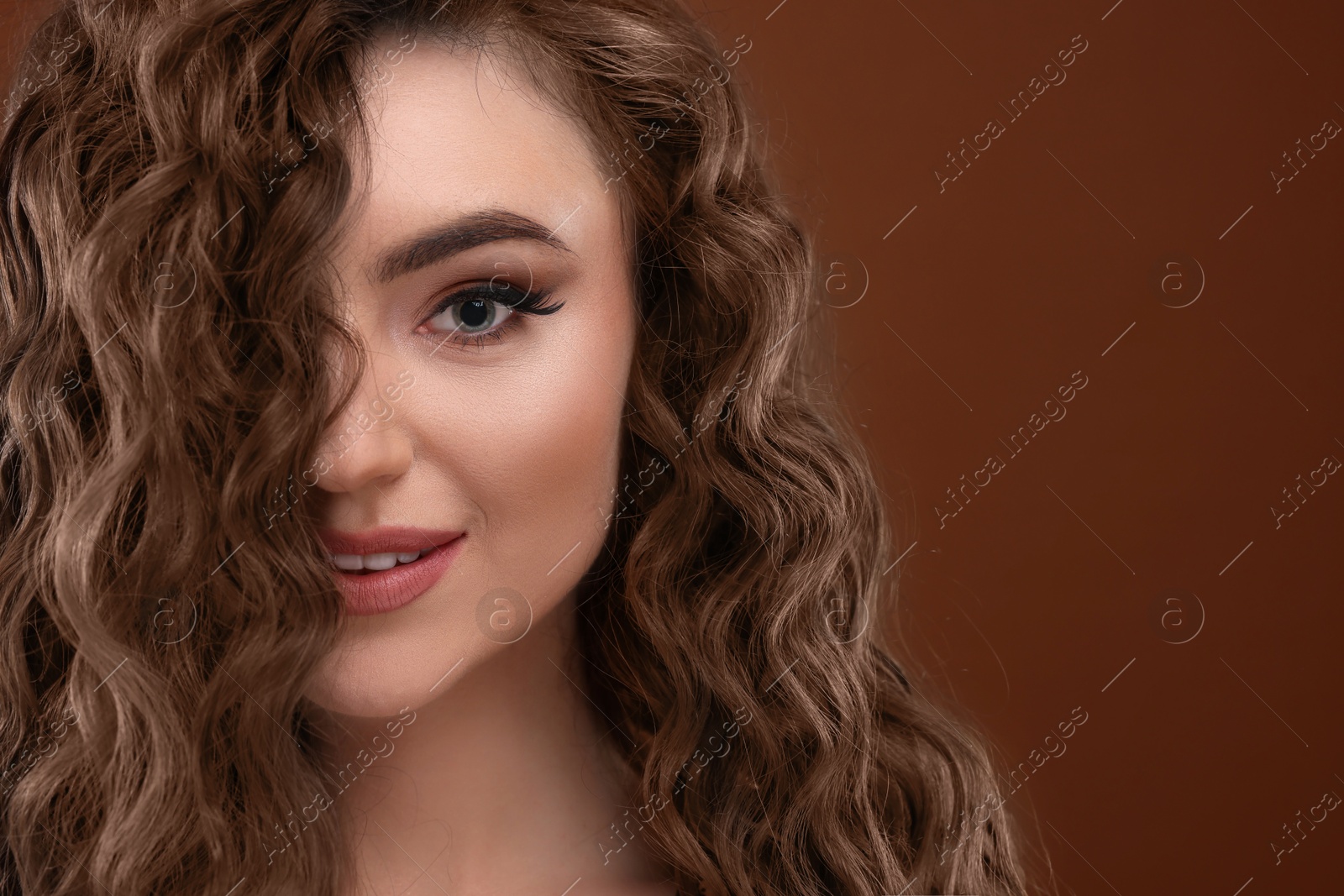 Image of Attractive woman with beautiful hair in mocha mousse shade on brown background, space for text. Trendy color of 2025 year