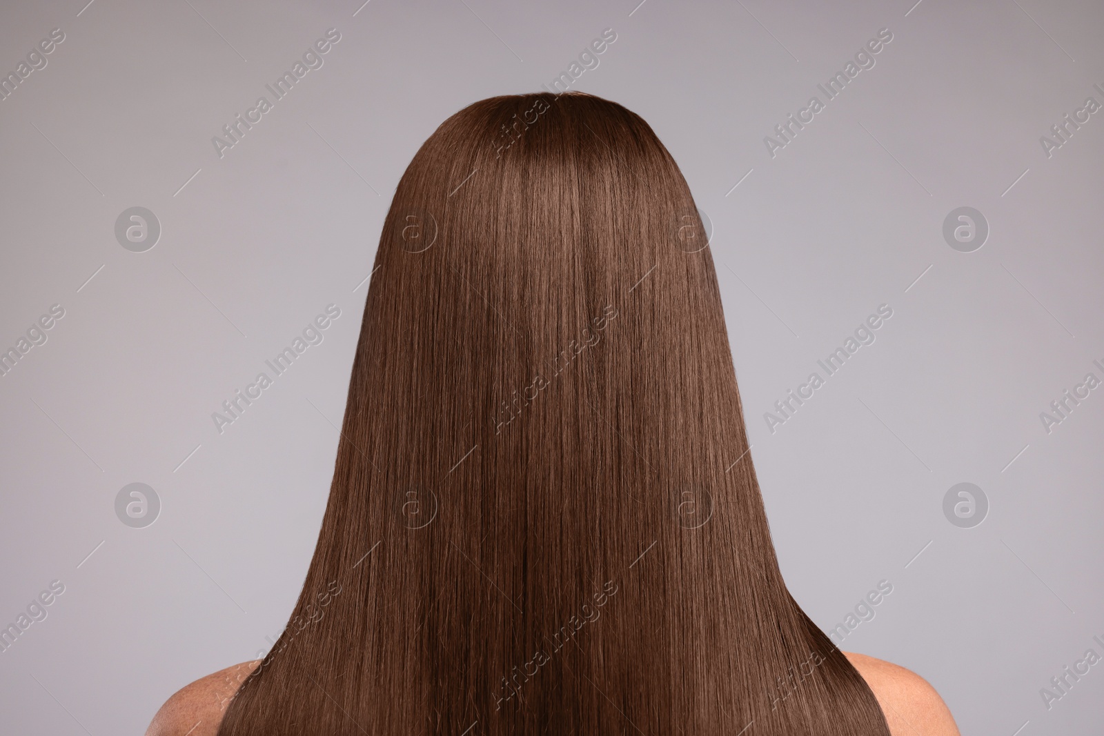 Image of Woman with beautiful hair in mocha mousse shade on grey background, back view. Trendy color of 2025 year