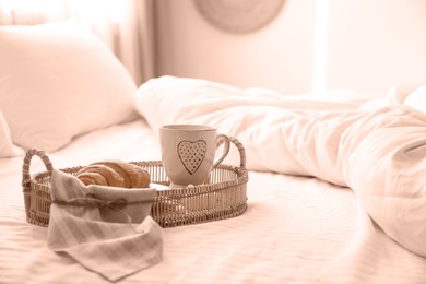 Image of Delicious morning coffee and croissant on bed, toned in mocha mousse shade. Trendy color of 2025 year