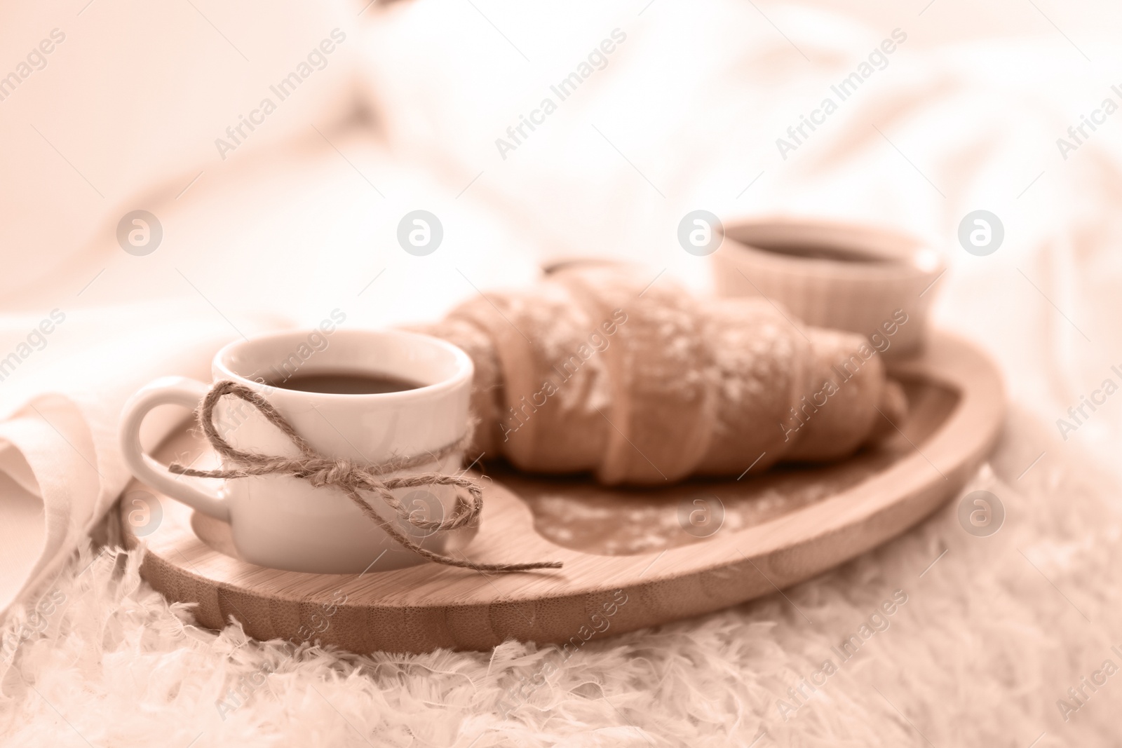 Image of Delicious morning coffee and croissant on bed, toned in mocha mousse shade. Trendy color of 2025 year